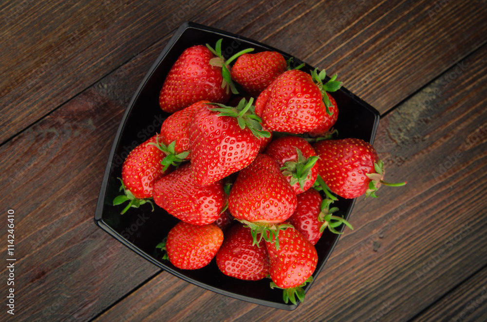 Wall mural Strawberries in black plate. wooden background top view