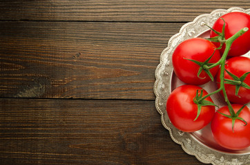 tomatoes on vintage plate top view, wooden background