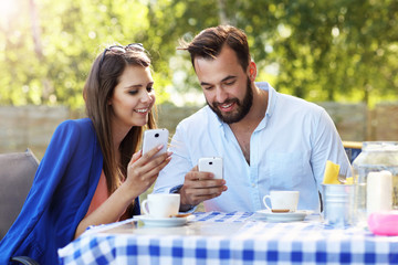 Young couple using smartphone in restaurant