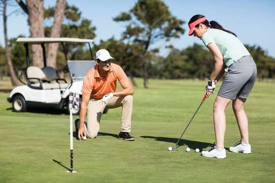 Woman playing golf while standing by man 