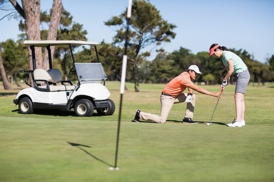 Man teaching woman playing golf 