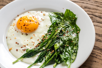 Fried egg with spinach on the wooden table