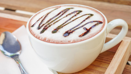 cup of cocoa with foam on wood table.and spoon
