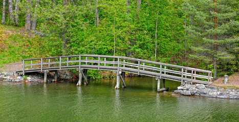 Fototapeta na wymiar Pedestrian wooden bridge over stream