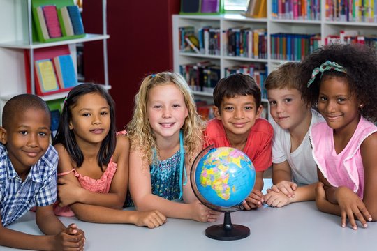 Smiling children with globe on table
