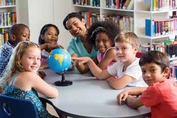Female teacher and children with globe on table 