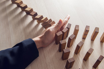 Businesswoman hand stopping the domino wooden effect concept for business.