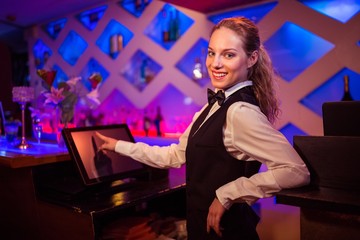Beautiful barmaid pointing at modern cash register