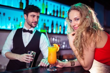 Woman leaning on counter while bartender in background