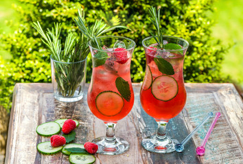 Pink gin and tonic cocktail with raspberries, cucumber and mint