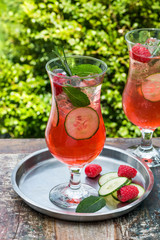 Pink gin and tonic cocktail with raspberries, cucumber and mint
