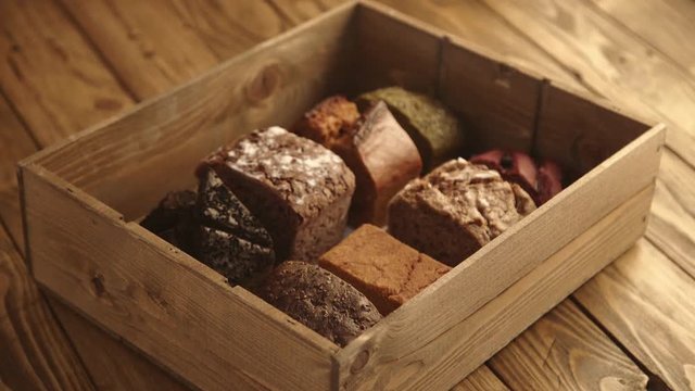 Hand moves from side with blank business card, above the wooden box with various bread samples inside in professional artisan bakery Business product presentation