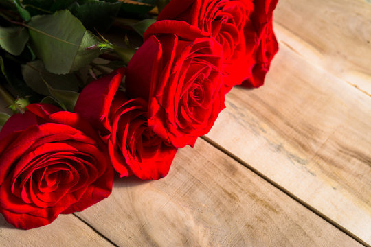 a bouquet of red roses lying on a wooden table
