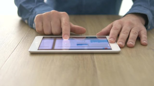 Businessman examining financial charts and business infographics on his touch screen tablet