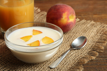delicious and juicy peaches in a glass bowl with yogurt on wooden background  and a glass of peach juice
