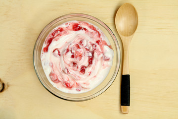 Bowl of strawberry yogurt with wooden spoon.