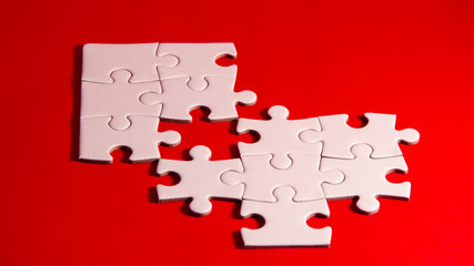 solving the puzzle, still life with a white jigsaw/puzzle incomplete over a red background, symbol of problem solving