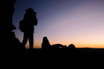 Silhouette of woman traveler shooting camera sunset