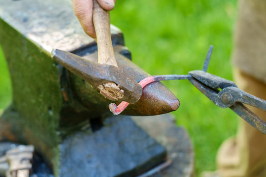 Blacksmith forging metal on anvil