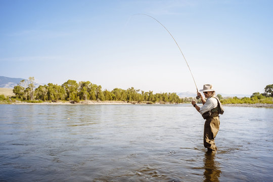 Man wearing waders fishing in river