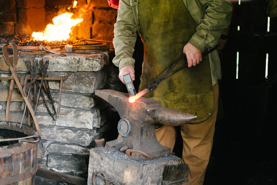 blacksmith forging red hot metal on anvil