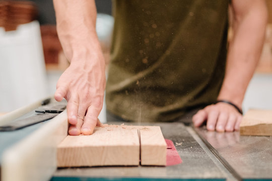 Carpenter cutting wood on table saw