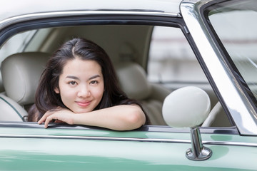 Asian lady smiling in a vintage car