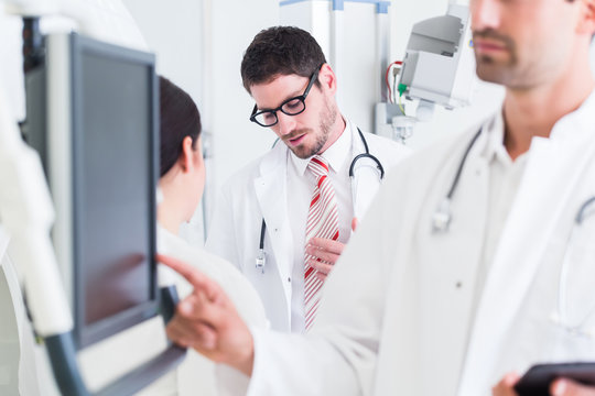 Arzt bei Diagnose am Bildschirm nach MRT Tomographie, das Team bei Diskussion im Hintergrund