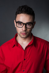 Man on black background in red shirt and glasses. Business style