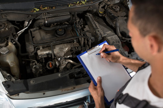 Mechanic checking list of car parts