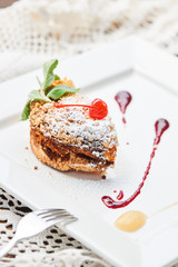 A sweet dessert consisting of crumble with applesauce and cherry topping served on a white plate