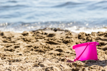 Small sand pail toy on summer beach.