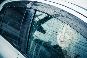 雨の日に車の中から外を見ている女性