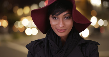 Fashionable Black woman with floppy red hat and overcoat on urba