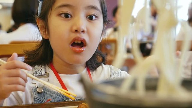 Slow motion of Asian girl eating Ramen noodle Japanese food in a restaurant.