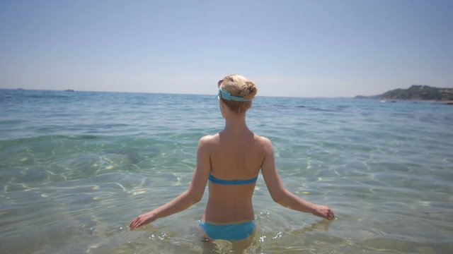 Sexy back of a beautiful woman on tropical beach in blue bikini