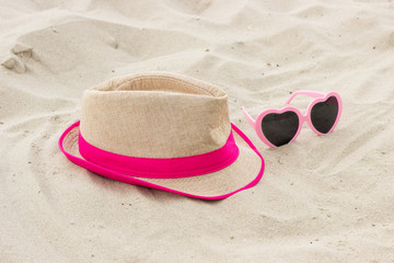 Fototapeta na wymiar Sunglasses and straw hat on sand at beach, sun protection, summer time