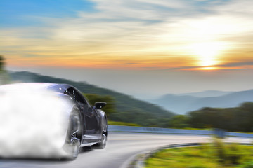 Brandless sport car drifting on the road under sunset. The smoke has covered the car and made it unidentifiable.