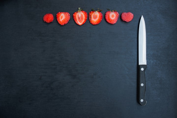 strawberries and knife on black background