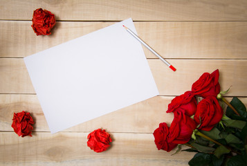 blank sheet of paper on the table beside him a bouquet of red ro