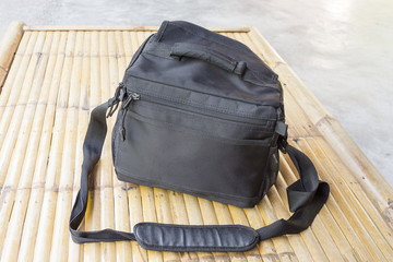 Black camera bag on bamboo floor. select focus front black camera bag.