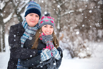 Loving couple embracing in winter park. Loving warm hands to each other. Copy space. The girl hat...