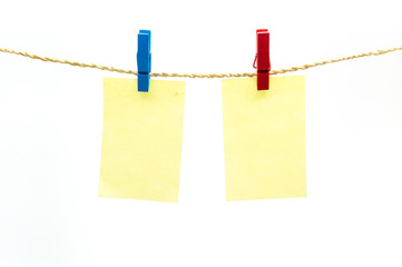 Red and blub clothespins and yellow note paper hanging on rope isolated white background