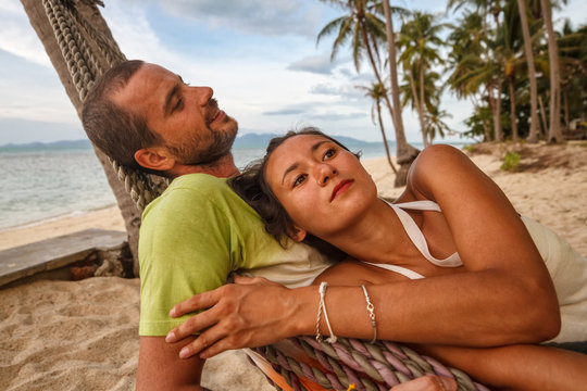 Young couple lying in a hammock on a tropical beach