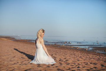 Fototapeta na wymiar beautiful girl in white dress sitting on the beach