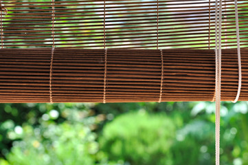 store bambou enroulé d'une fenêtre donnant sur jardin 