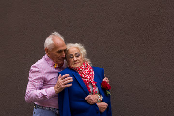 An old man gently embraces the elderly woman.