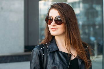 Stylish young woman in leather jacket and sunglasses  