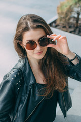 Stylish young woman in leather jacket and sunglasses 