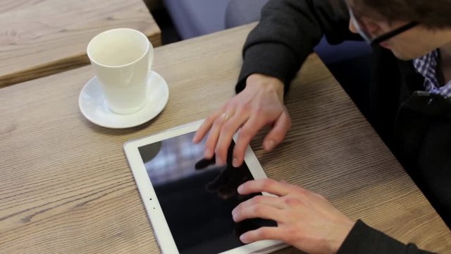 Man in a Cafe Drinking Tea and Working with Tablet